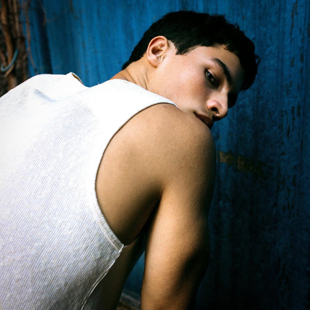 Handsome man wears Parke & Ronen Muscle tee and looks back over his shoulder.