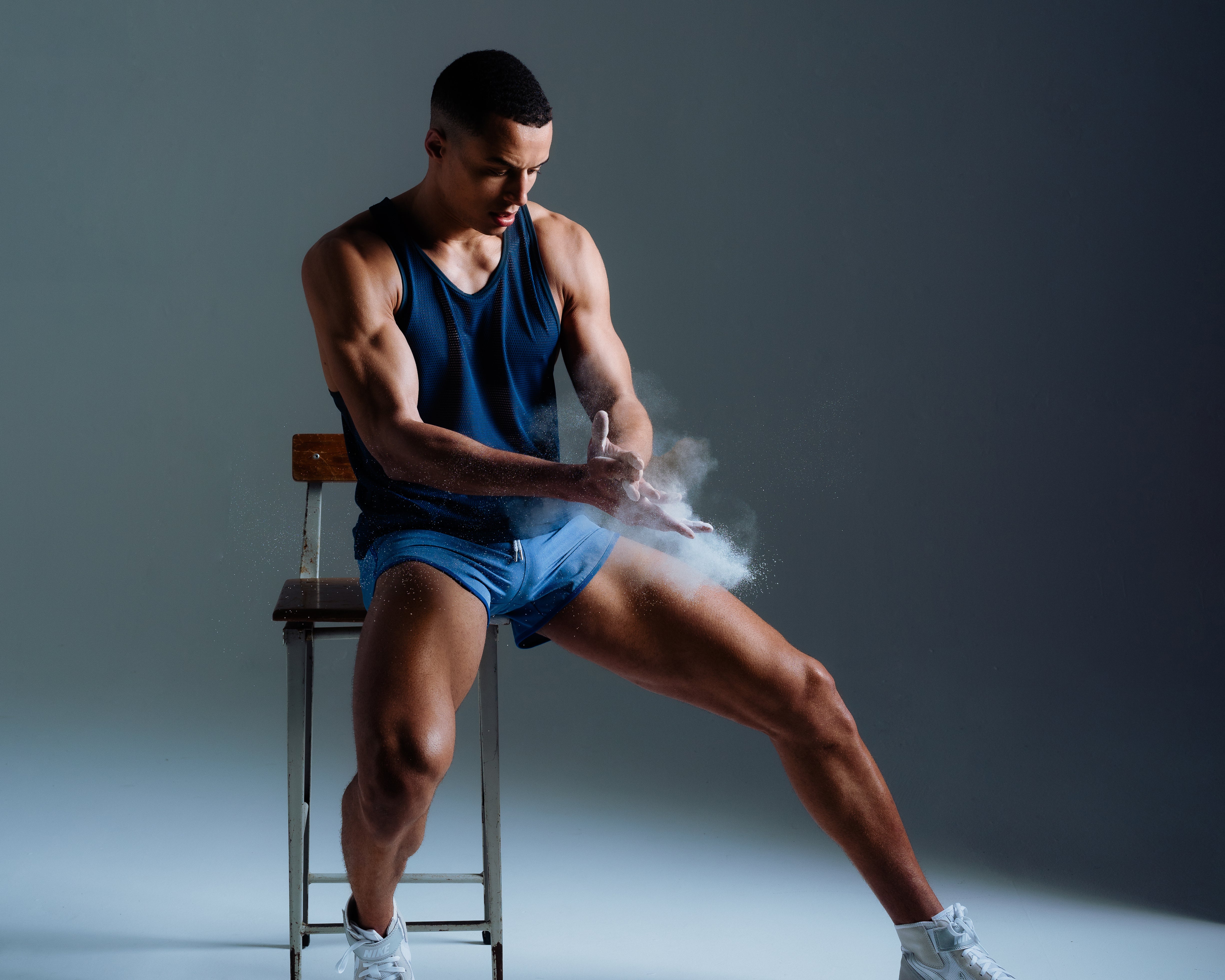 Parke & Ronen Actionwear campaign image. Male model is seated wearing mesh tank and action runner shorts.